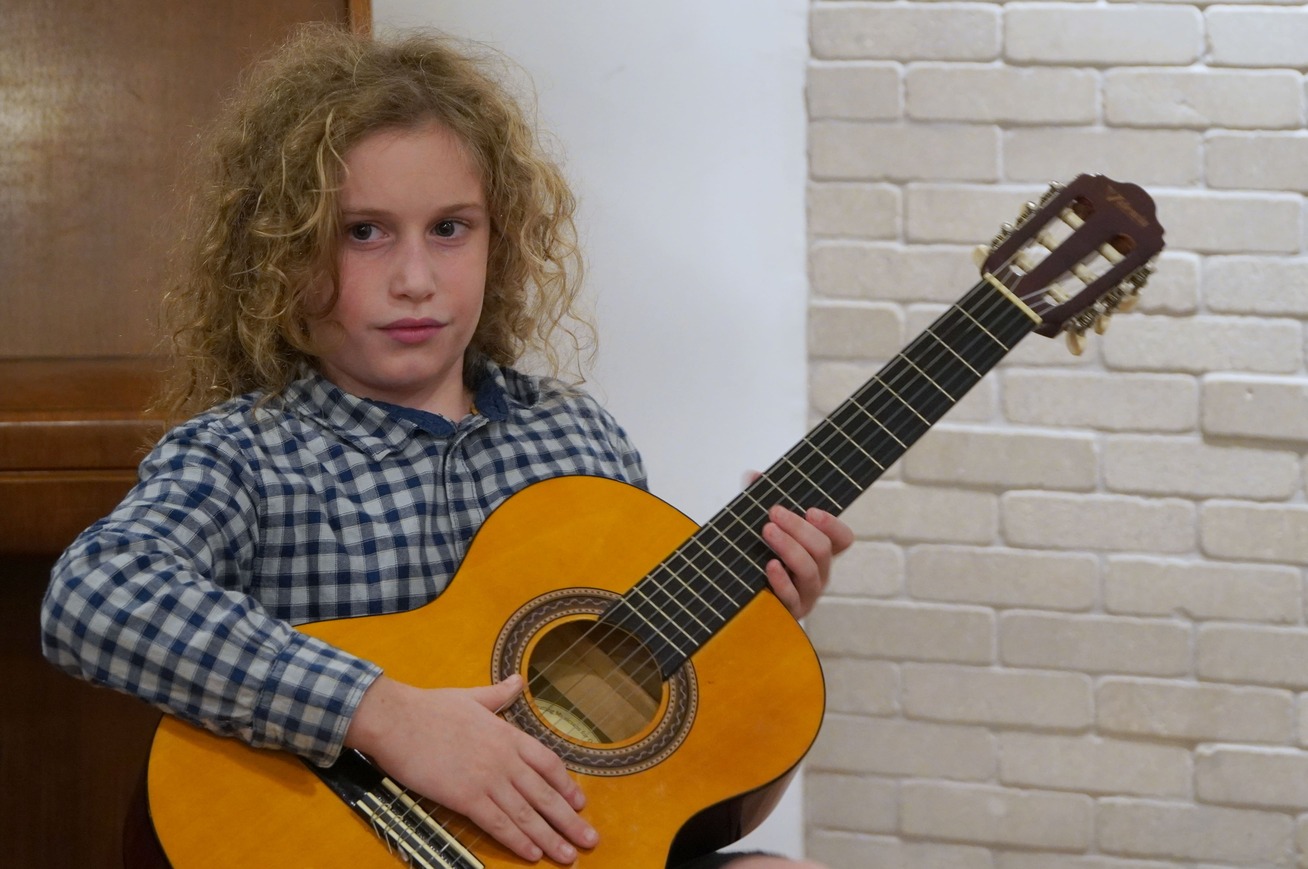 ילד לומד גיטרה קלאסית בסטודיו ברחובות